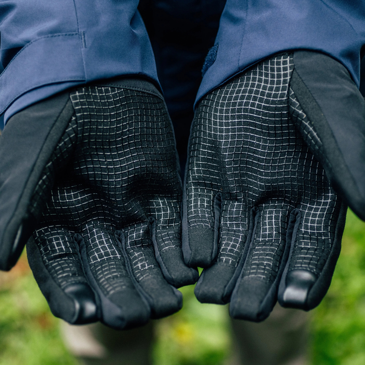 Close-up of a person wearing Trekmates Unisex Friktion Gore-Tex Waterproof Gloves Black TM-008647, shown against a blurred outdoor background.