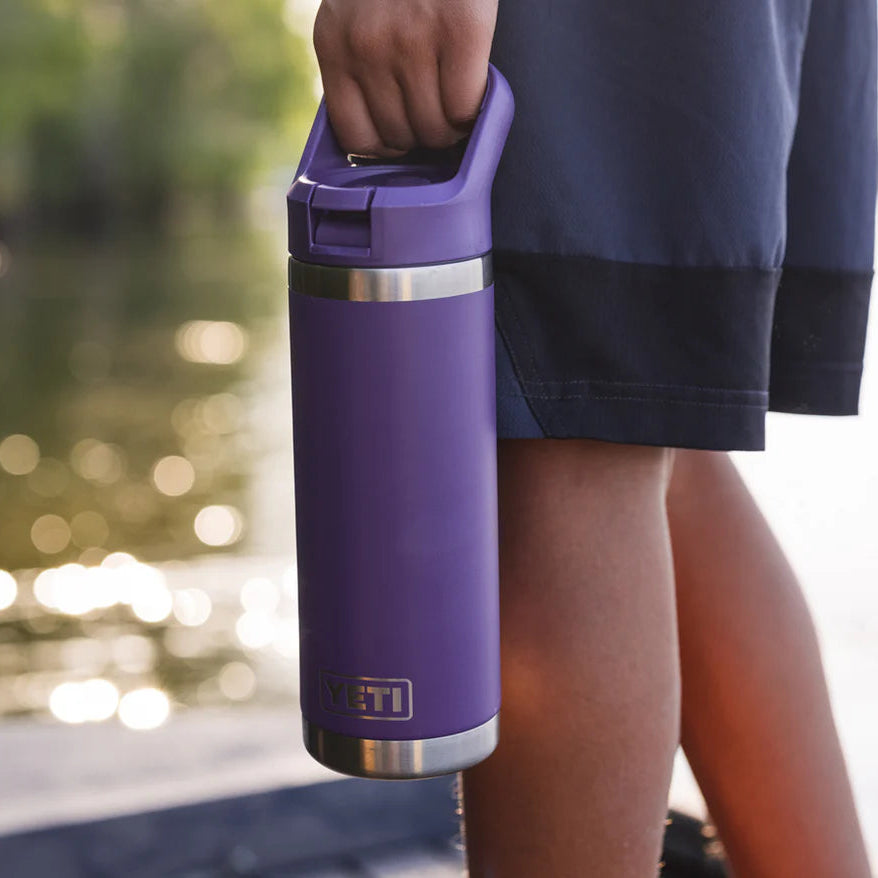 Person holding a purple Yeti rambler insulated bottle with colour matched straw lid with a blurred natural background