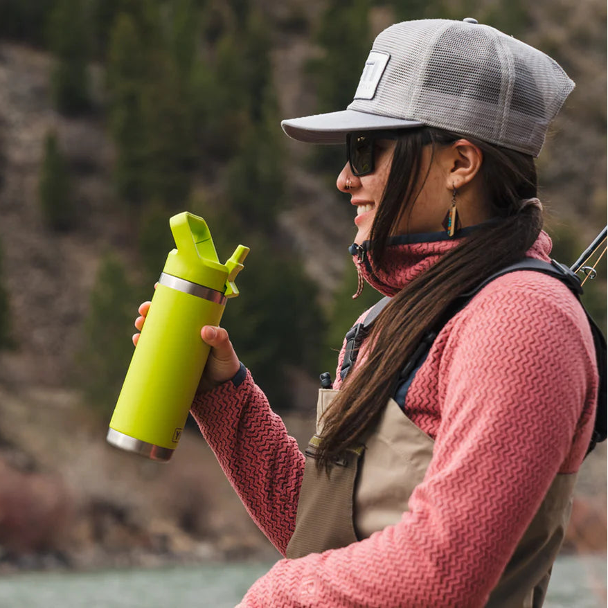 Person holding a green Yeti rambler insulated water bottle with colour straw cap on a fishing boat
