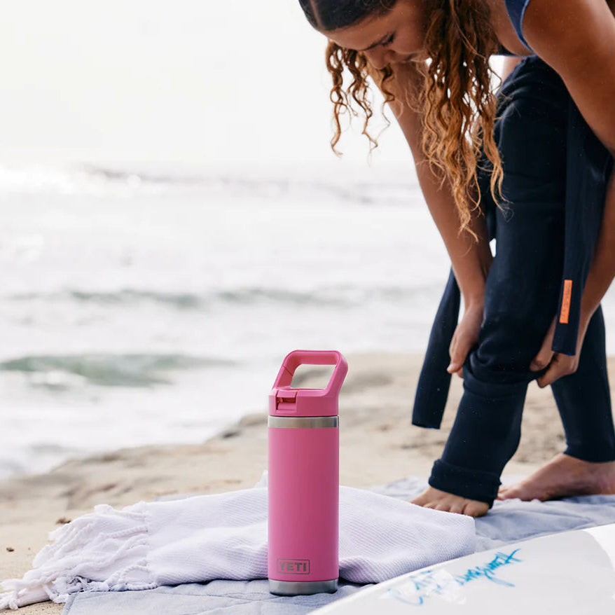 Person on a beach with a pink Yeti rambler colour straw cap bottle