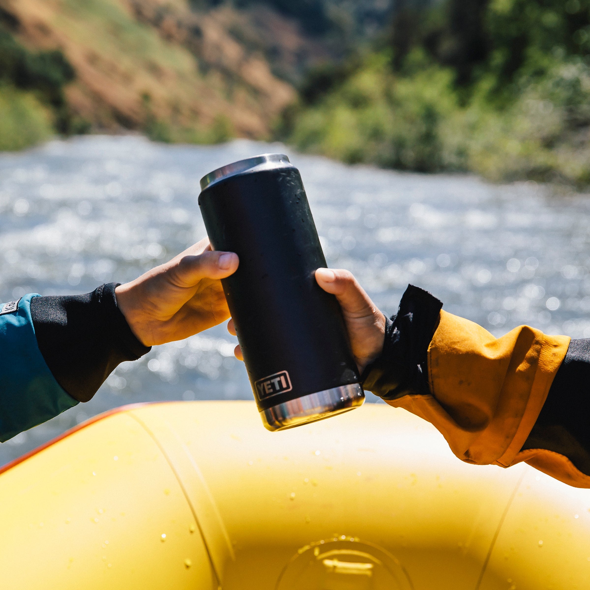 Two people holding a Yeti Rambler 26oz Chug Cap Bottle Yeti-Chug-26oz on a  raft on a river 