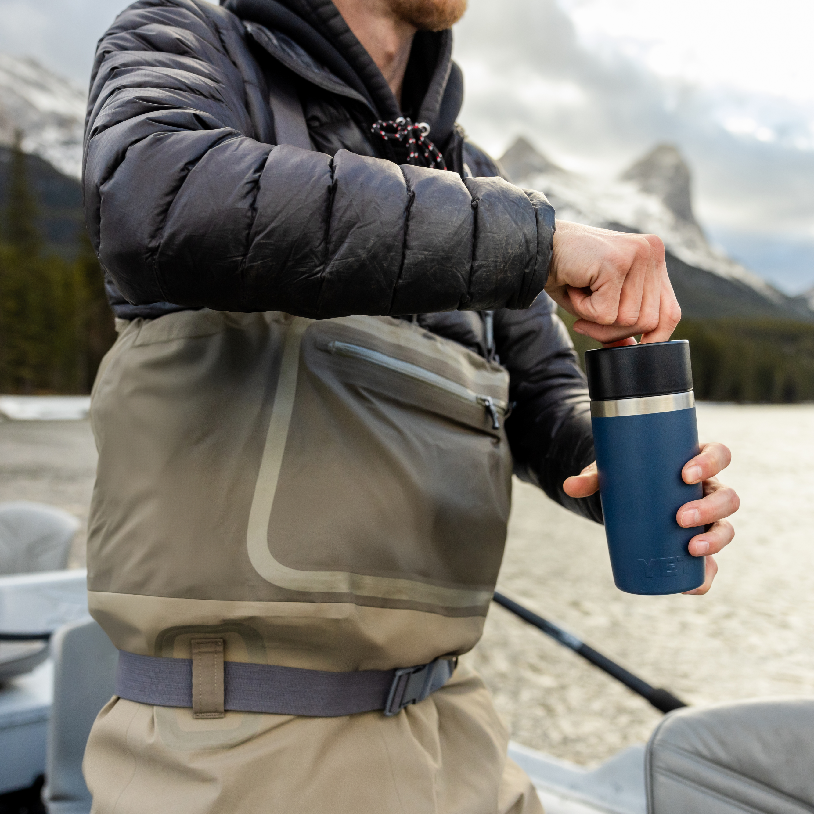 Person holding a Yeti Rambler Travel Bottle with Commuter Cap 12oz 355ml Rescue Red 70000002831 Yeti-RamblerBottle-12oz with mountains and lake in the background
