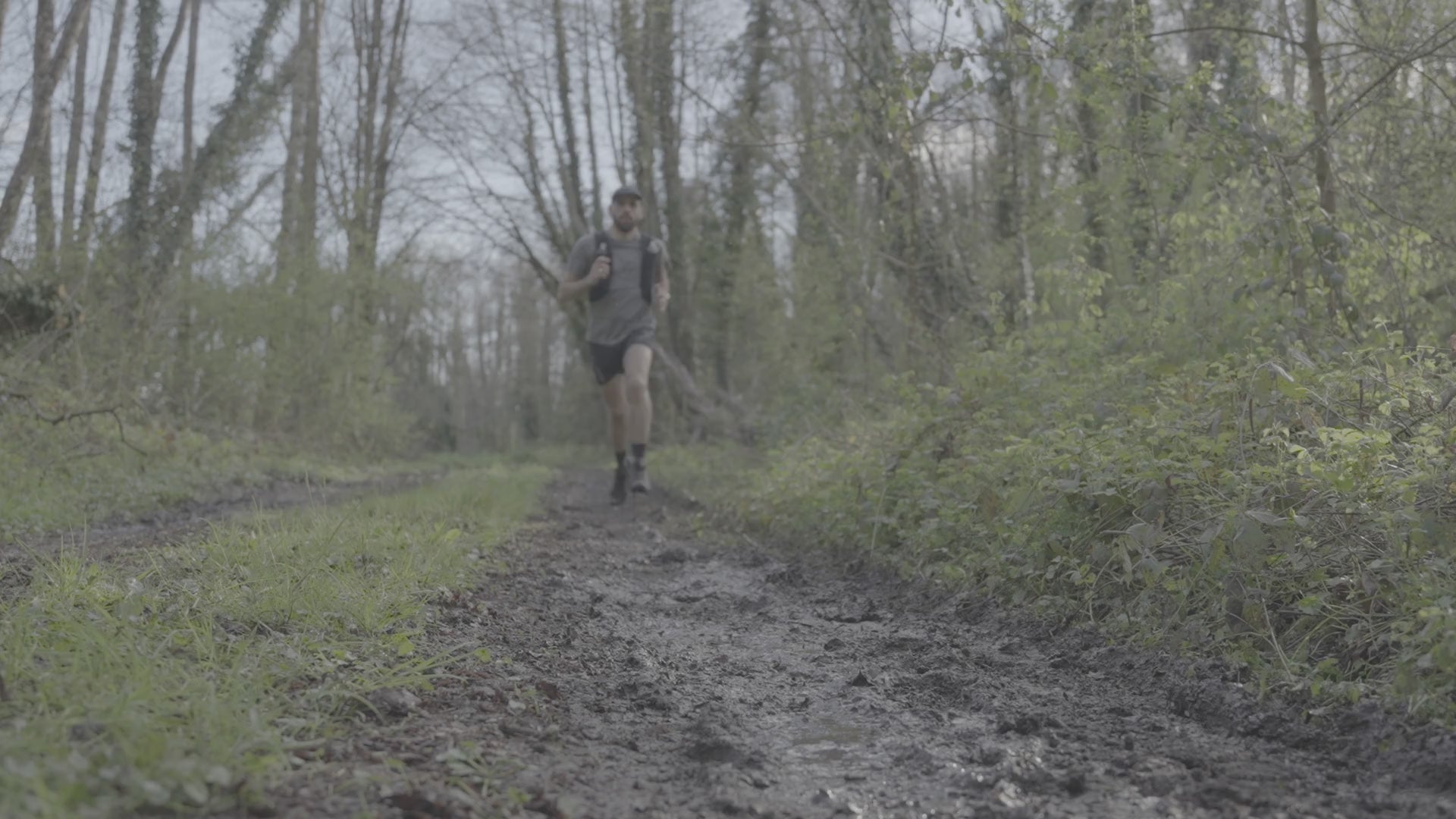 Video of man wearing Salomon Men's Speedcross 6 Trail Running Shoes Black Phantom L41737900 running through a muddy forest trail