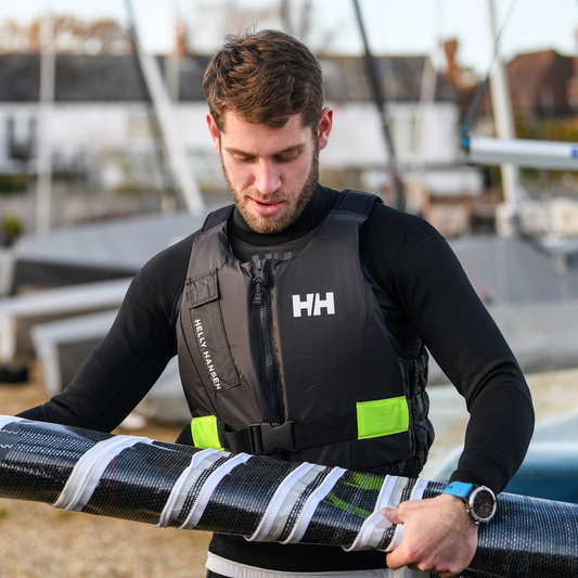 Man wearing Helly Hansen Unisex Rider Vest 50N Buoyancy Aid Ebony 980 33820 with sailing boats in the background